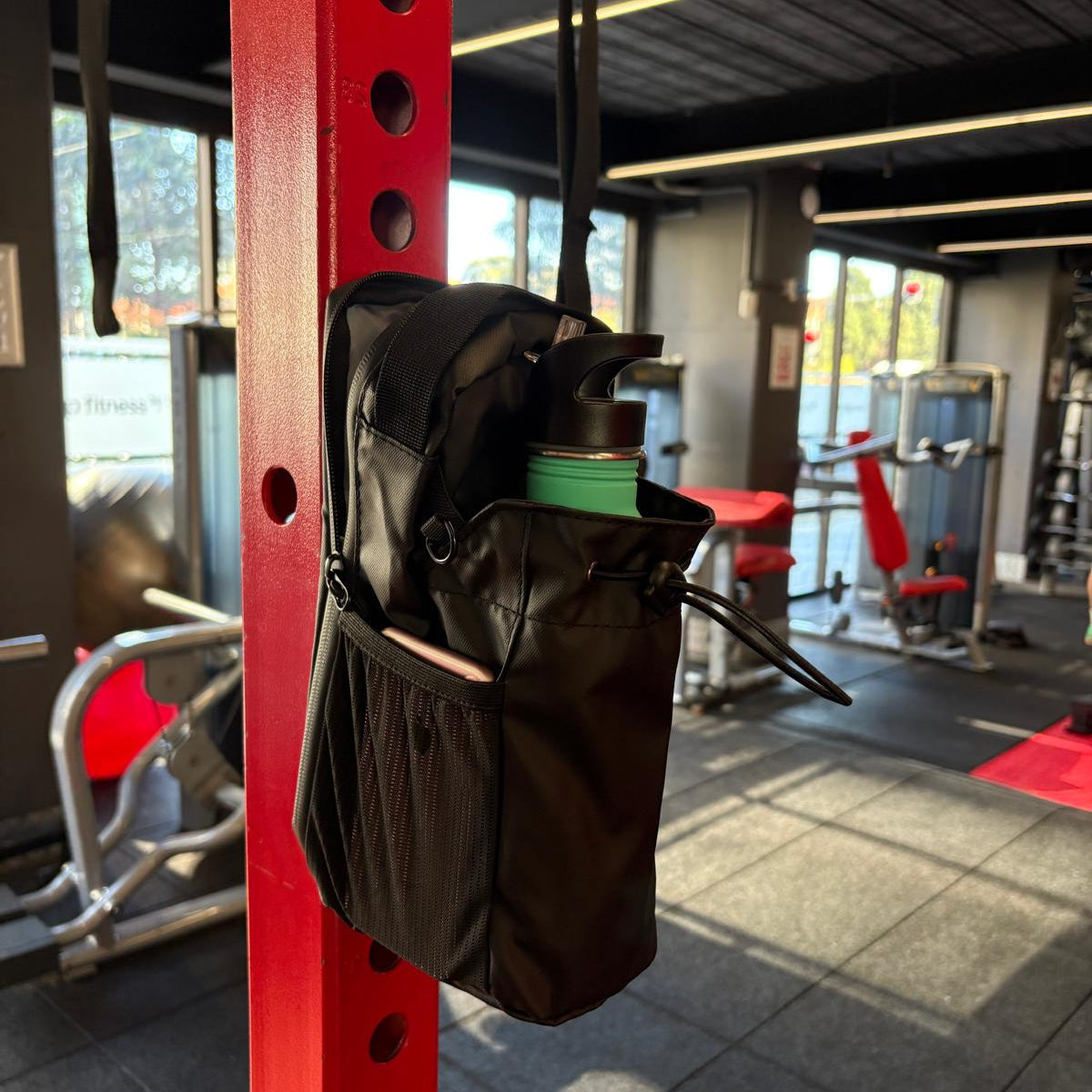 Black Smart Magnetic Gym Bag attached on a Cycling Work out Machine in a gym setting