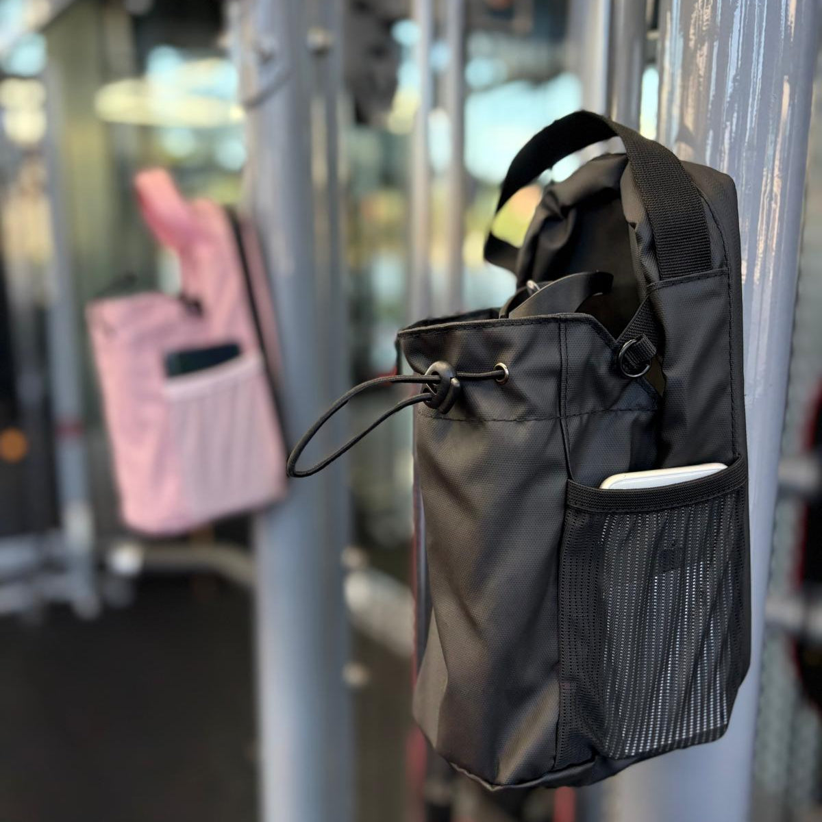 Black and Pink Smart Magnetic Gym Bag attached on a metal Work out Machine in a gym setting