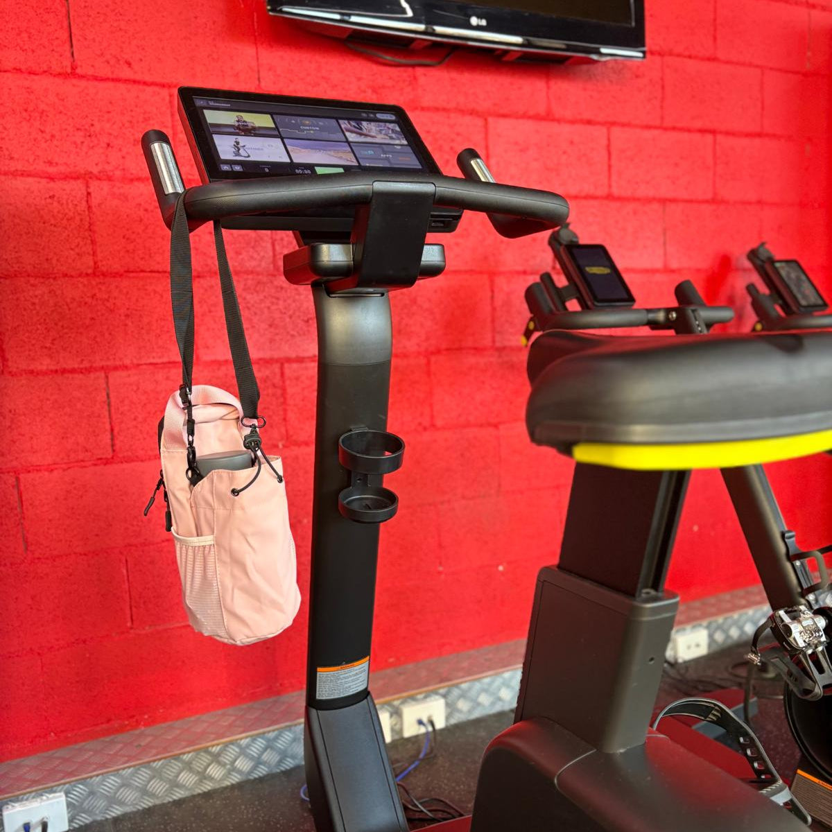 Pink Smart Magnetic Gym Bag hanging on a Cycling Work out Machine in a gym setting